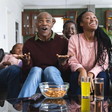 Parents and child sitting on the sofa watching a movie — spending quiet evening with parents