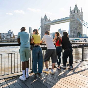 Youth leaning over railing with London Bridge in background