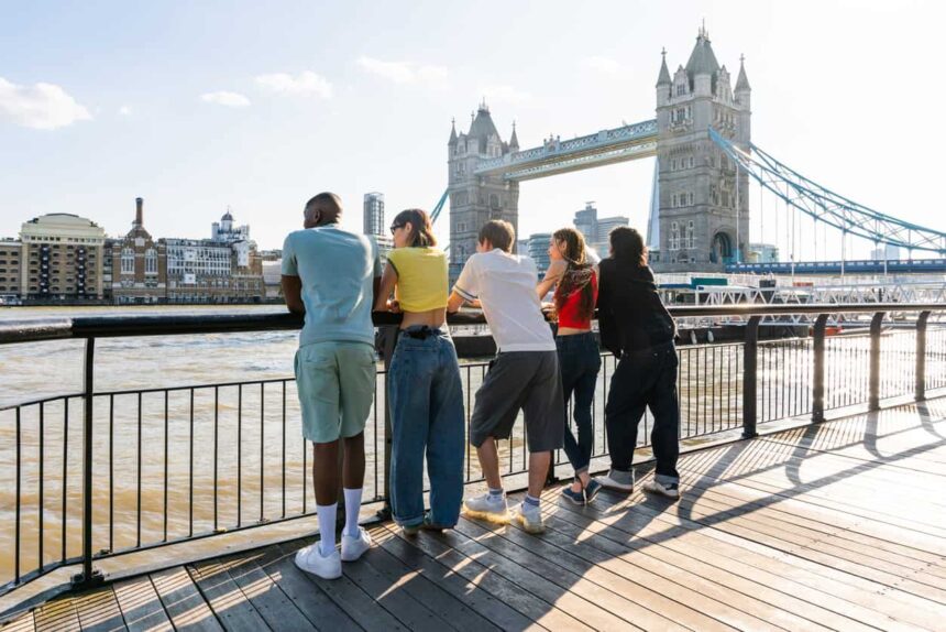 Youth leaning over railing with London Bridge in background