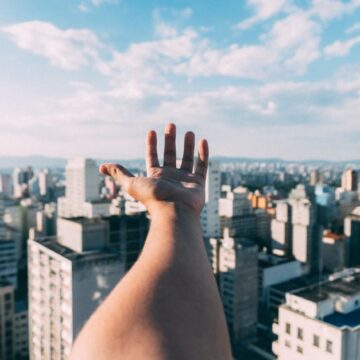 A young hand stretching out towards corporate buildings, proving that Gen Z are Business