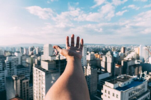 A young hand stretching out towards corporate buildings, proving that Gen Z are Business