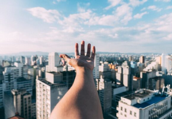 A young hand stretching out towards corporate buildings, proving that Gen Z are Business