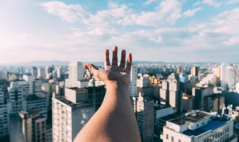 A young hand stretching out towards corporate buildings, proving that Gen Z are Business