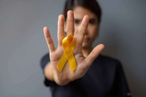 Young person holding the suicide prevention ribbon: one out of four young uk teens who commit suicide 