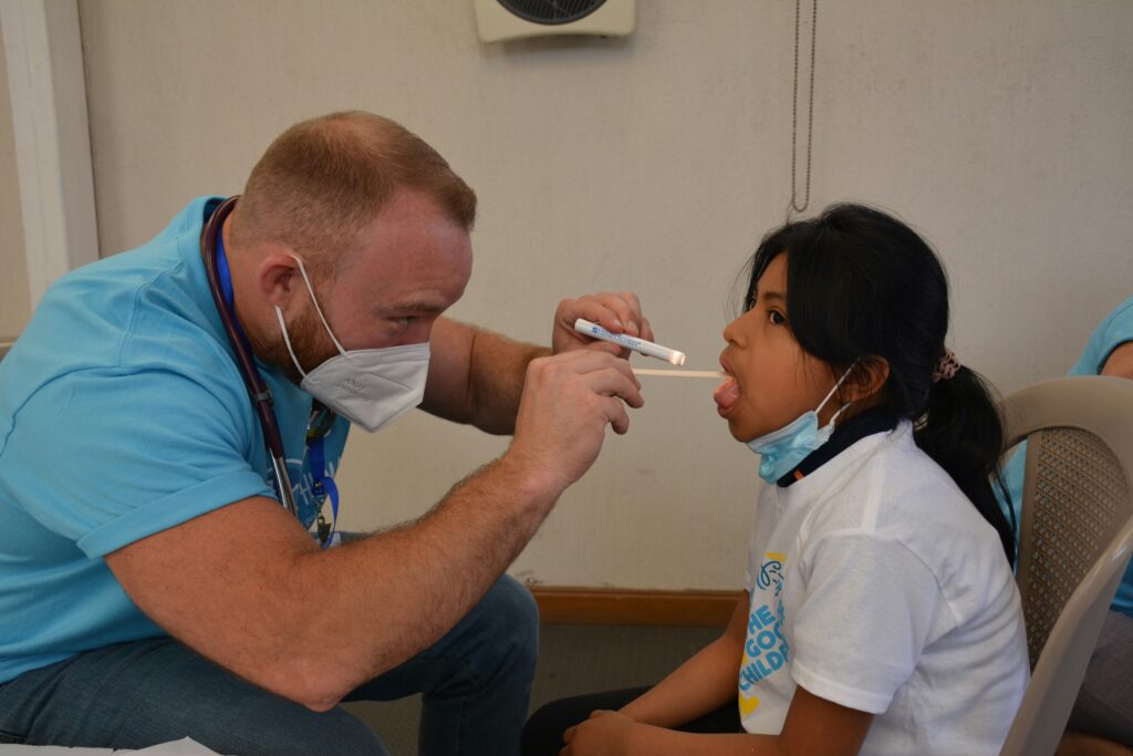 A photograph of a nurse swapping for flu/virus symptoms in a child's mouth.