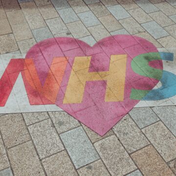Photograph of the NHS logo painted on the floor with a heart around it.