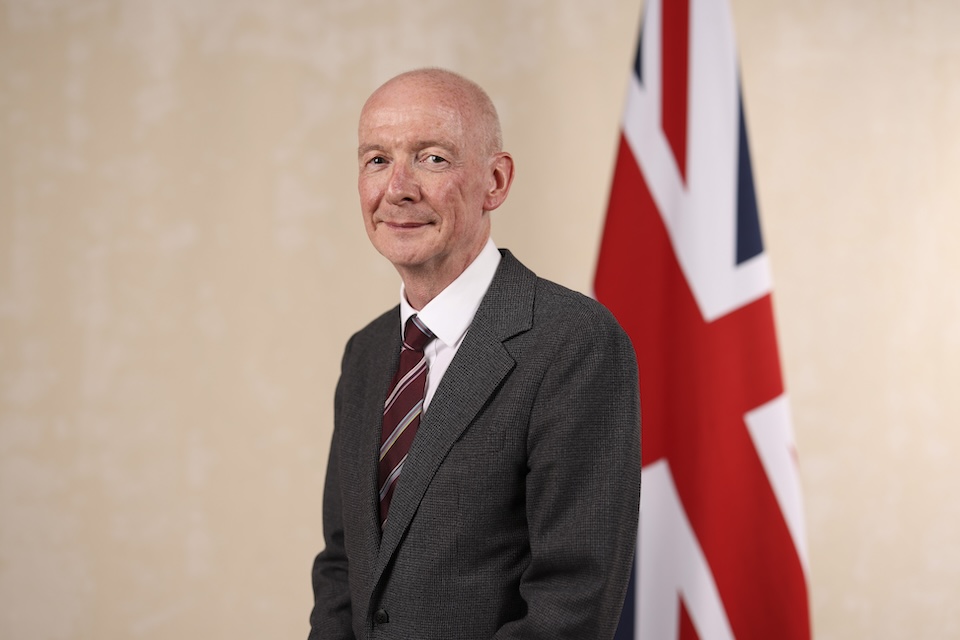 Pat McFadden stood beside the Union Jack flag. Photo Credit: Gov UK