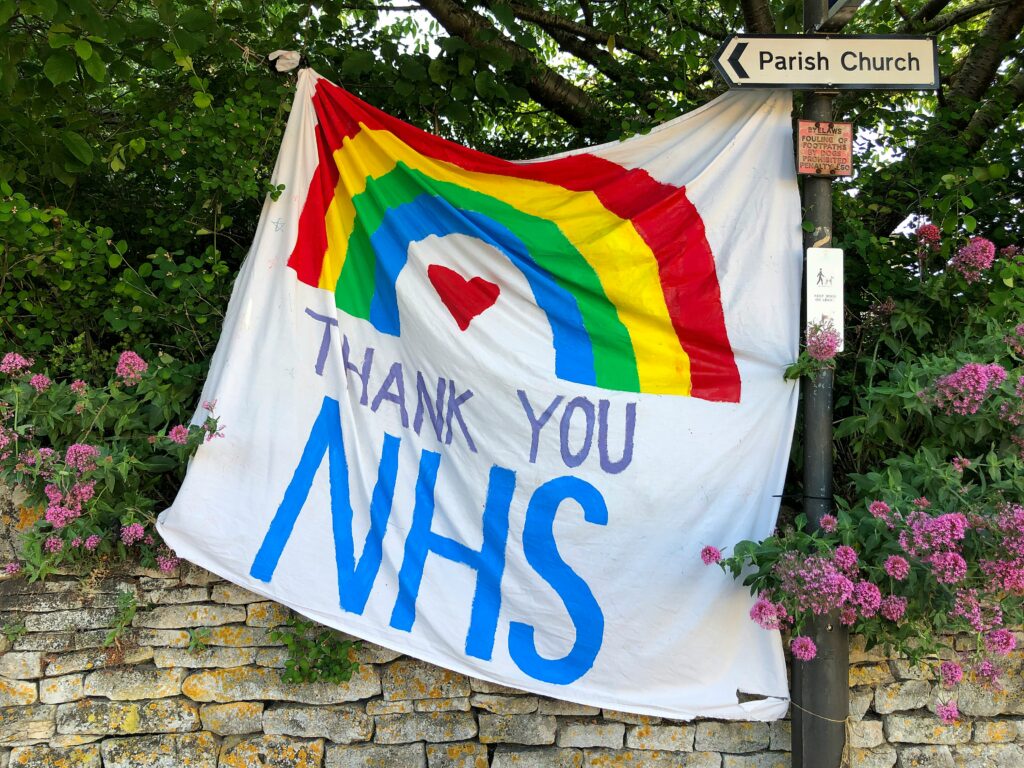 Photograph of a banner with the words 'thank you NHS' written on it, alongside a rainbow.