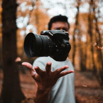 Photograph of a camera floating above someone's hand.