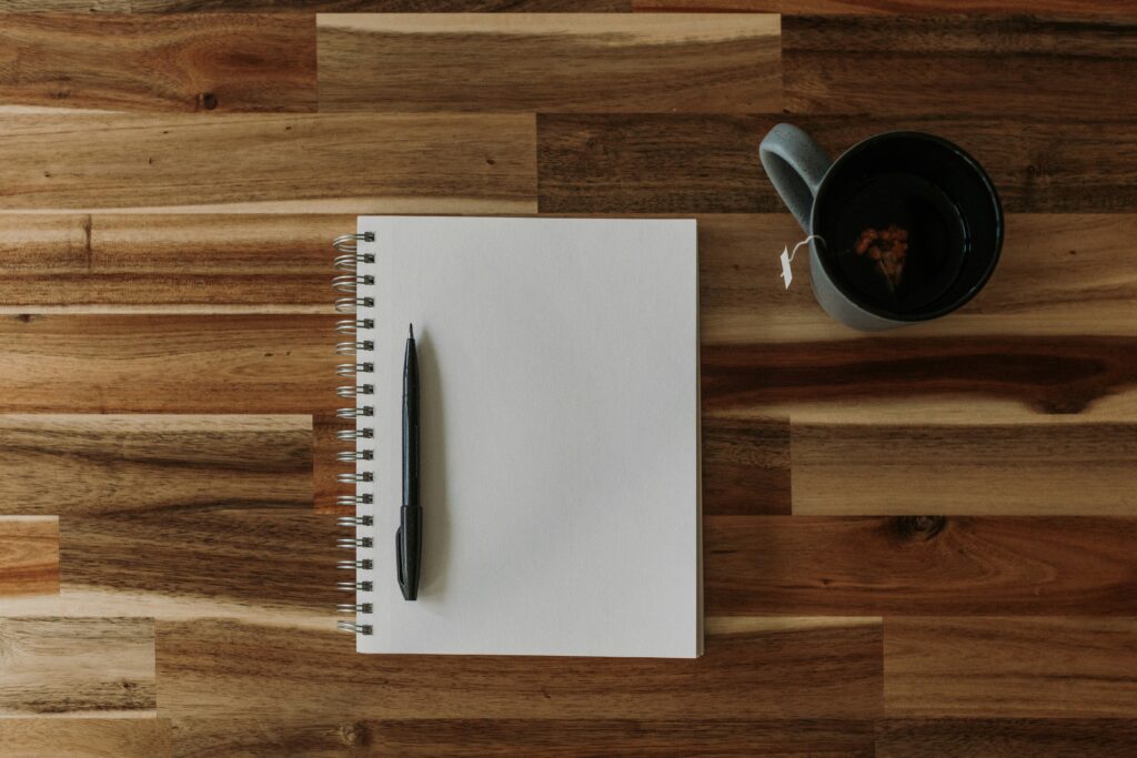 Photograph of a notebook, pen and coffee.