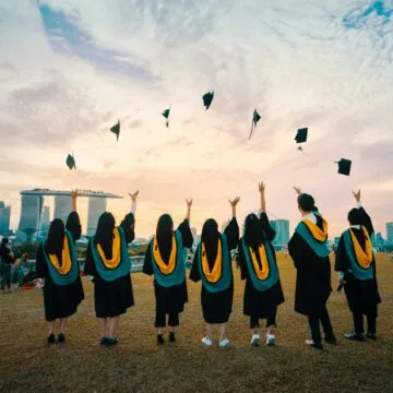 Photograph of university students throwing their graduation hats in the air.